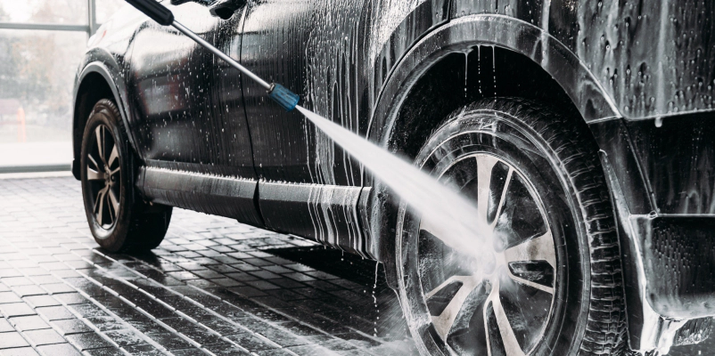 A car being washed with a hose and water jet.