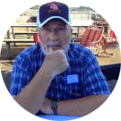 A man with a beard and hat sitting at a table.